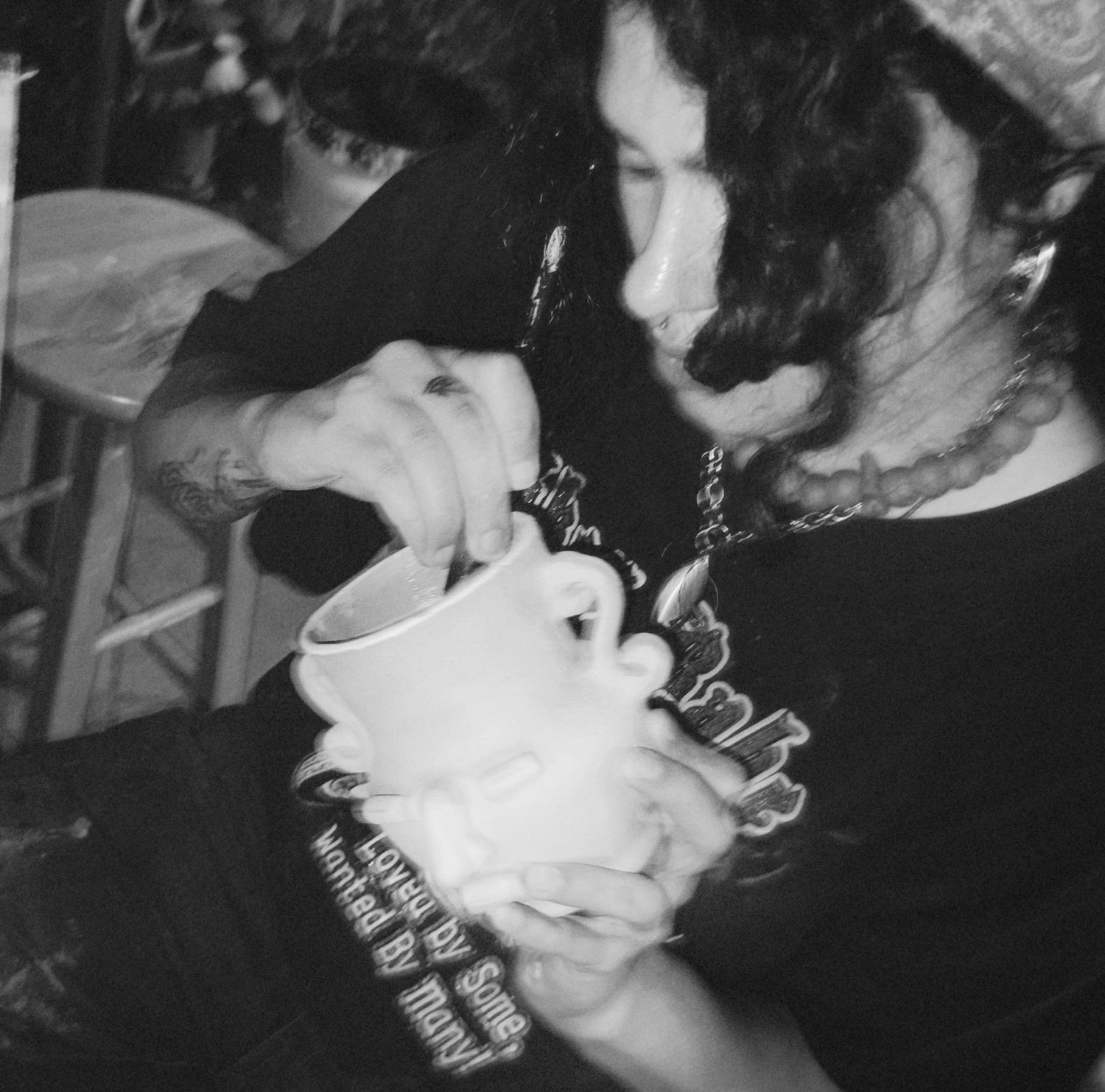 Person holding a face mug with a unique design, wearing a black shirt with text.